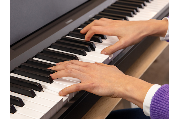 The hands of a person playing the P-145 digital piano