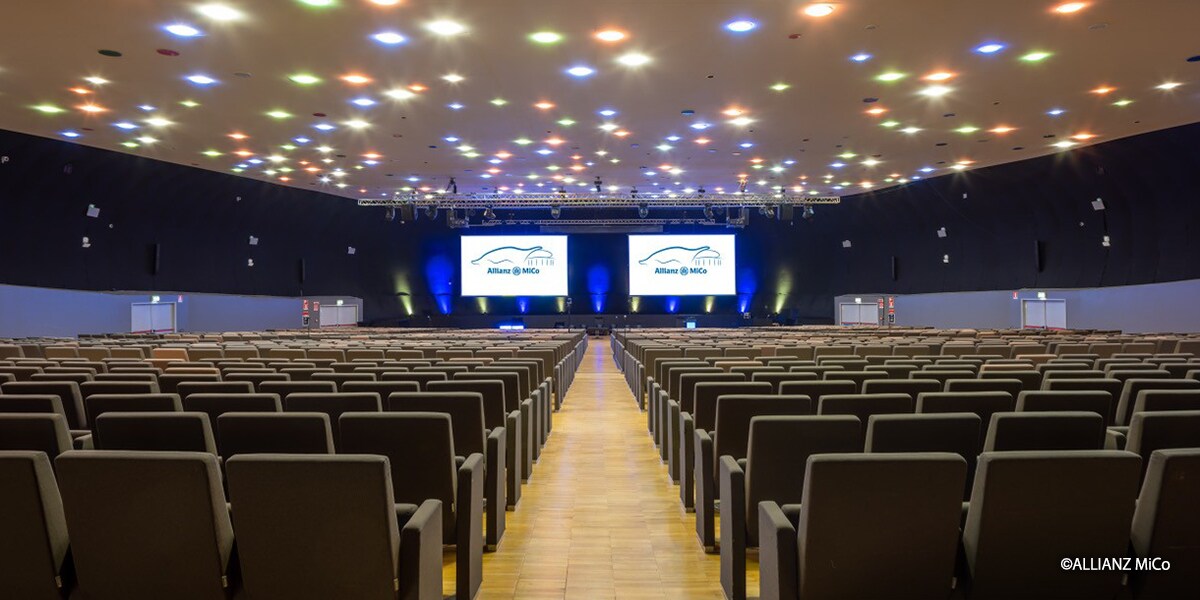 Large auditorium at Allianz MiCo in Milan with tiered seating, dual presentation screens and integrated Yamaha Pro Audio sound system for conferences and events.